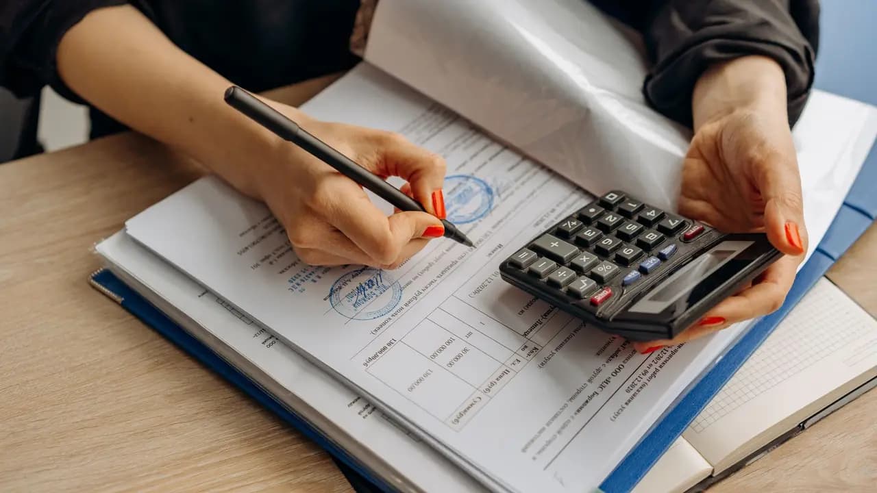 An accountant working through paperwork with a calculator